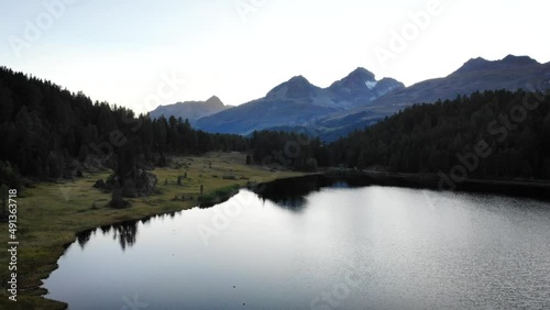Aerial flyover at sunset over lake Staz in St. Moritz, Switzerland with a view of the Engadin valley and its surrounding peaks photo