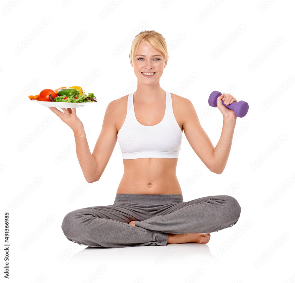 Good food and exercise - The perfect combo. Portrait of a beautiful young woman holding a salad in one hand and a dumbbell in the other.