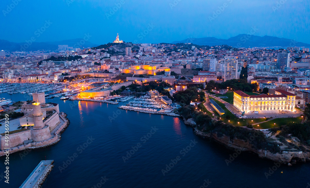Aerial view of old port, Tour du Fanal and Basilica of Notre Dame at Marseille, France at night