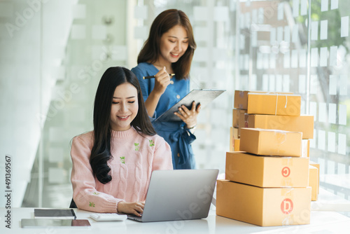 Startup small business owner working with computer at workplace. Freelance two woman seller check product order. Packing goods for delivery to customer. Online selling. E-commerce. Online Shopping © PaeGAG