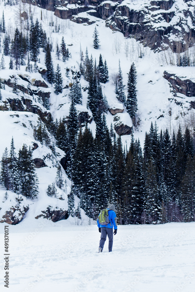 Man in blue hikes through snow9i