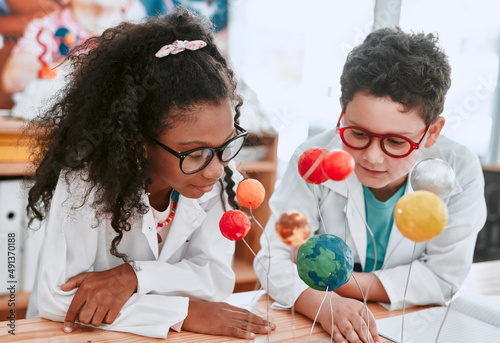 The solar system is so vast and interesting. Shot of two adorable young school pupils learning about planets and the solar system in science class at school.