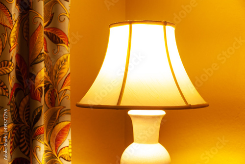 A cozy nook in the room with a curtain and a table lamp that illuminates the room with soft yellow light.