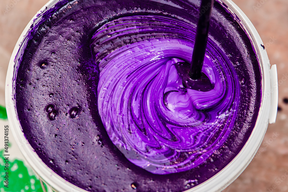 Purple wall paint. Stirring in a bucket of paint for repairs. Purple wall paint. Stirring in a bucket of paint for repairs.