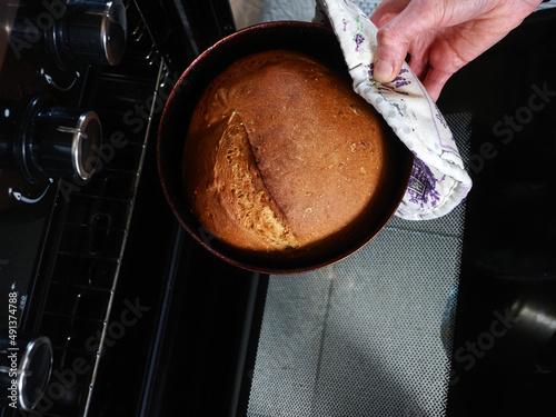 woman takes out bread baked from an oven © Elroi