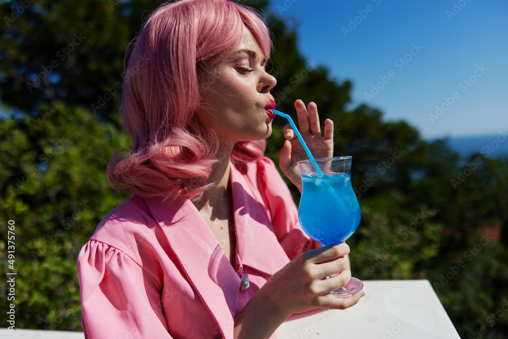 Delighted young girl enjoying a colorful cocktail hotel terrace Happy female relaxing