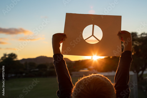 Bild auf Leinwand Little child holding up peace symbol against a beautiful sunset