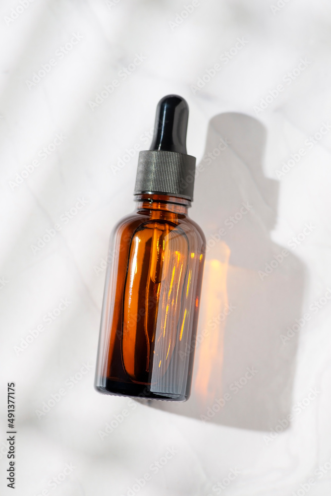 Amber glass bottles with dropper pipette with serum or essential oil on a white background. Skincare cosmetic with beautiful shadows. Beauty concept for face body care. Place for text