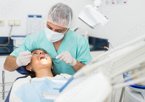 Portret of male dentist and woman patient sitting in medical chair during checkup at dental clinic office