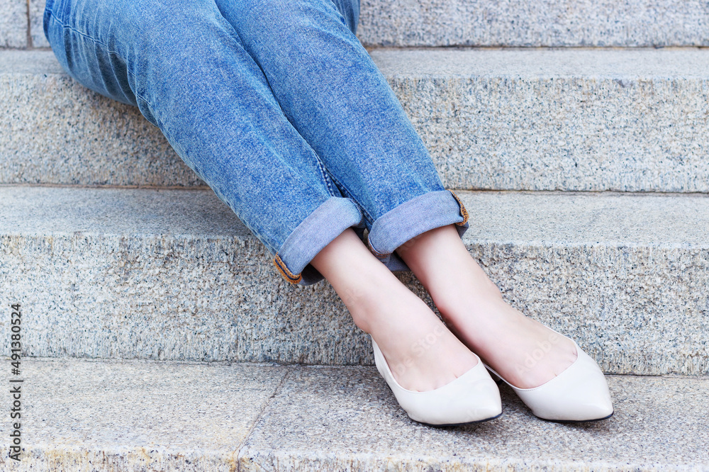 Female legs in jeans and shoes on background of concrete staircase. Female legs in jeans and shoes on background of concrete staircase.