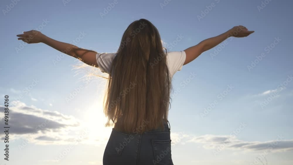 Happiness concept.young girl with her hair down, with hands up, stands with her back raised her hands, enjoying blue sky, sun. Girl dreaming raising her hands up to sky, enjoying happiness. Happiness concept.young girl with her hair down, with hands up, stands with her back raised her hands, enjoying blue sky, sun. Girl dreaming raising her hands up to sky, enjoying happiness.