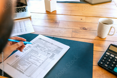 Fotografi Unrecognizable taxpayer filling in individual income tax return