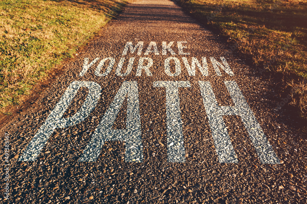 Obraz premium Make your own path motivational quote on footpath leading through park in diminishing perspective