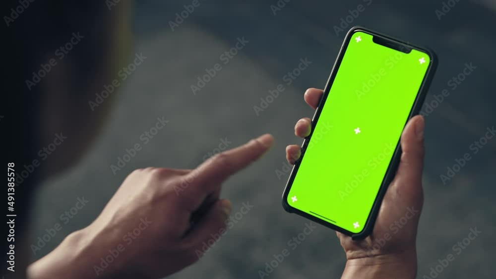 back view of fitness woman using green screen smart phone at home. Woman preparing for workout using smart phone.Woman doing a tap on mobile phone while resting during fitness training