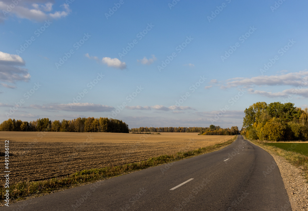 a lonely winding paved road through a field