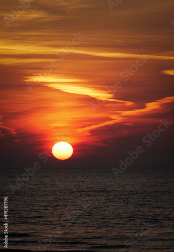 sun setting in the sea with cloud trails