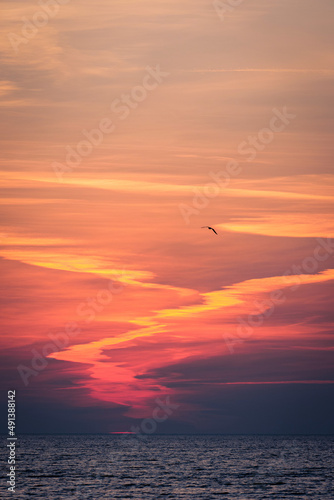 sun setting in the sea with cloud trails