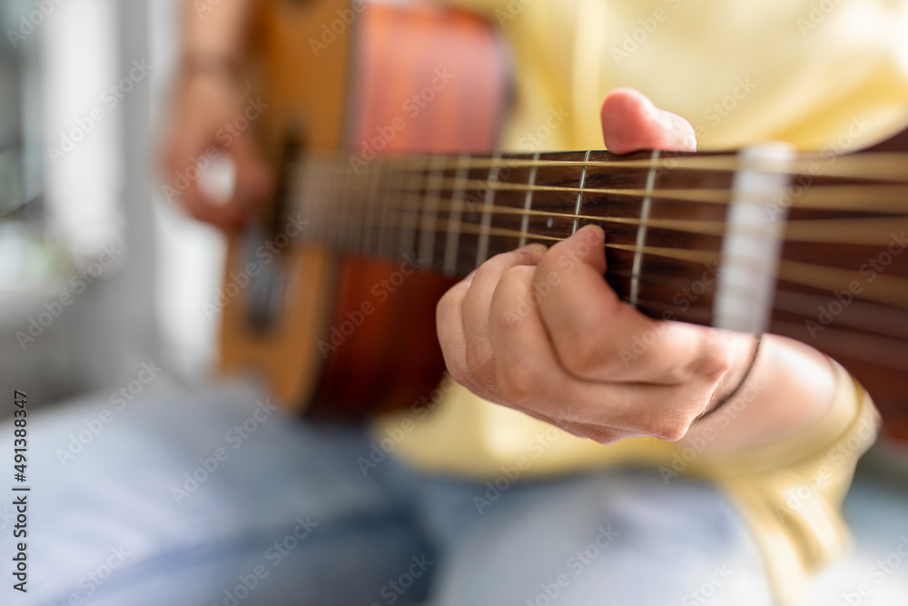 leisure, music and people concept - close up of man playing guitar sitting on windowsill