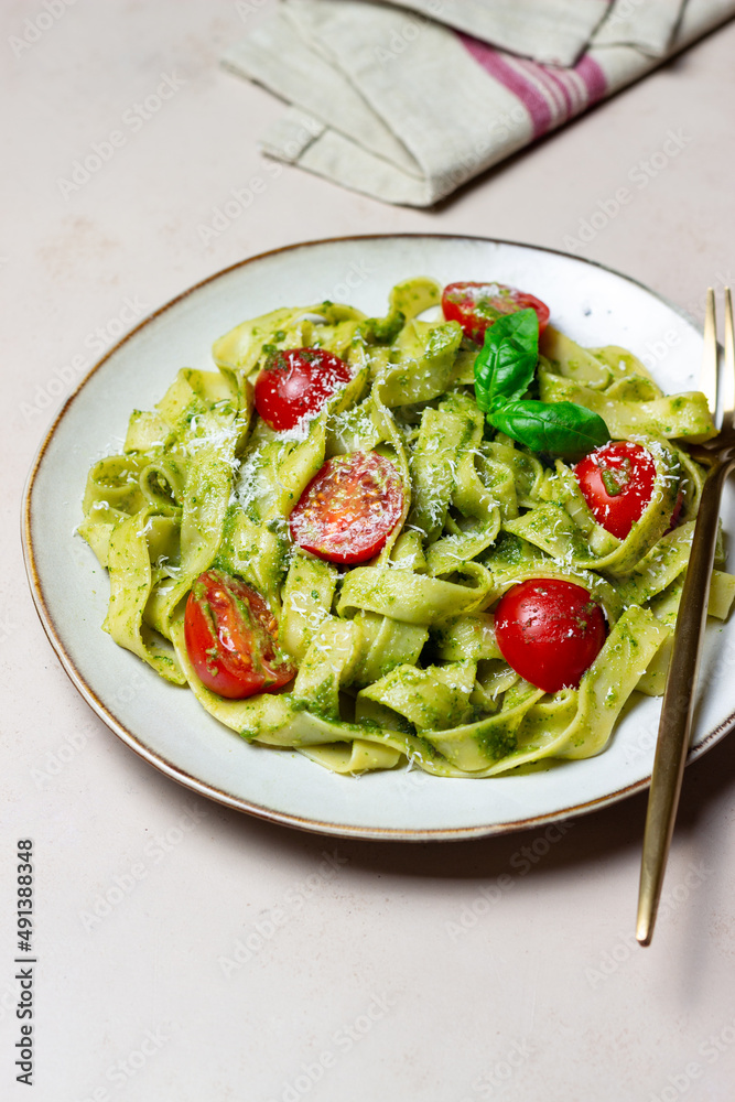 Linguini pasta with pesto sauce, tomatoes and cheese. Healthy eating. Vegetarian food. Italian cuisine.