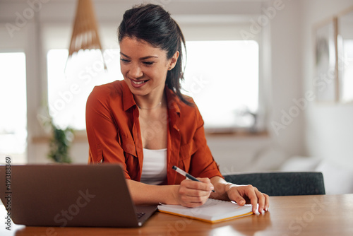 Diligent caucasian woman, taking notes during a meeting online.