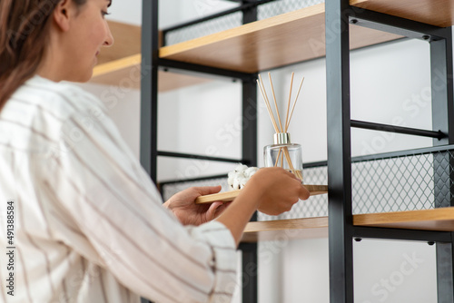 home improvement, decoration and people concept - close up of woman placing aroma reed diffuser to shelf