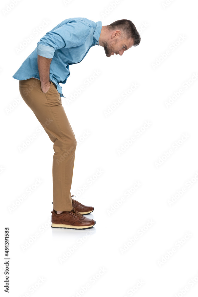 Naklejka premium middle aged man with hands in pockets looking down