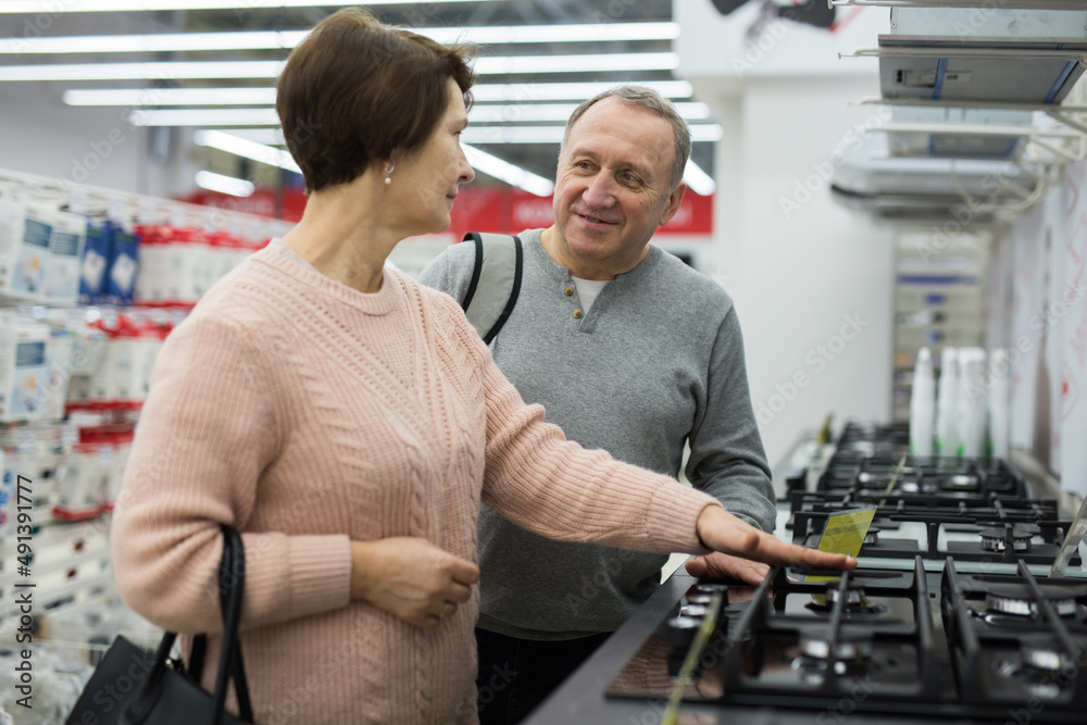 Senior couple choosing gas stove while shopping in appliance store.