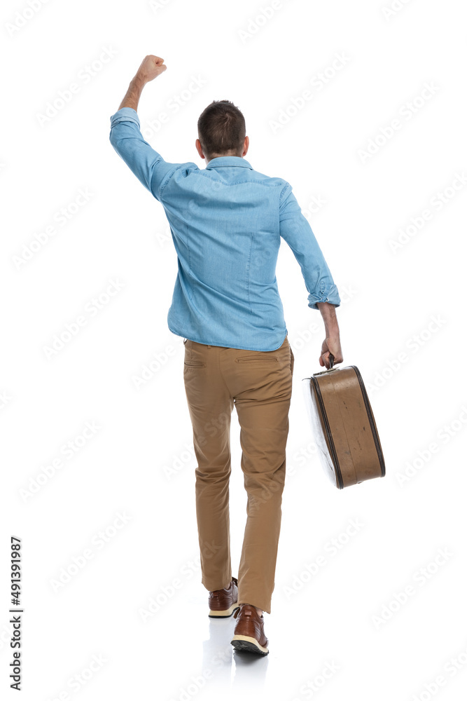 man with baggage holding fist in the air, celebrating freedom and travelling around the world man with baggage holding fist in the air, celebrating freedom and travelling around the world