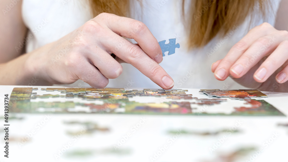 Fototapeta premium the girl collects puzzles in close-up