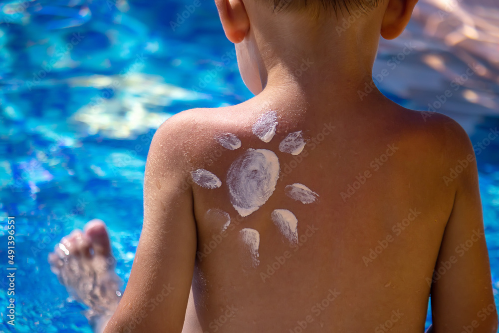 Mother puts cream on her son's back. Caring for baby skin. Sunscreens in the travel. selective focus Mother puts cream on her son's back. Caring for baby skin. Sunscreens in the travel. selective focus