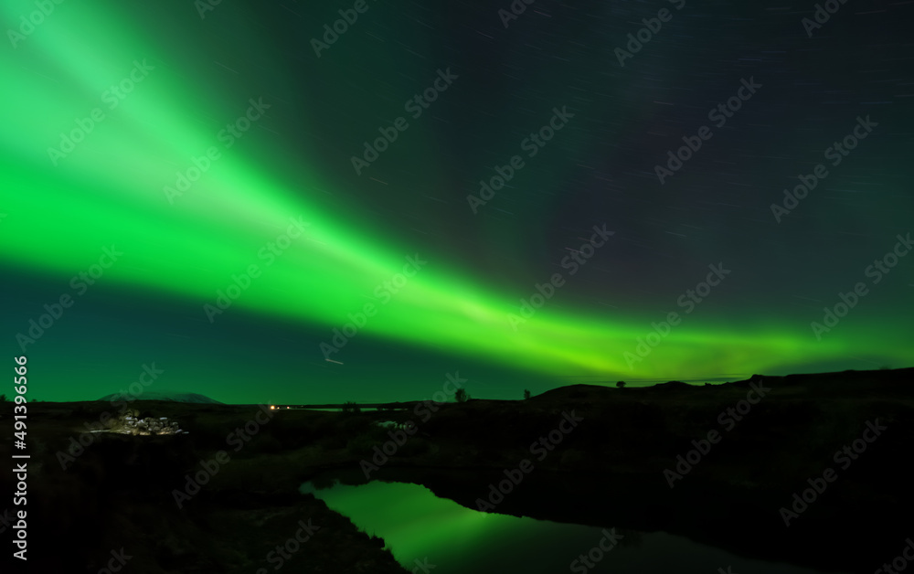 Aurora borealis long exposure with star trail and lake