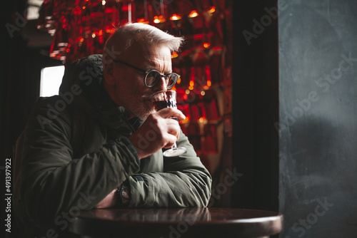 Senior man enjoying cherry liqueur in a pub. Tasting red wine in the wine cellar.