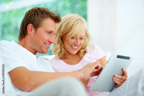 Happy couple using tablet pc. Happy couple sitting on a sofa using tablet pc.