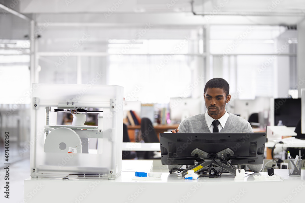 3D printing is the way forward. Cropped shot of a young man printing his designs on a 3D printer. 3D printing is the way forward. Cropped shot of a young man printing his designs on a 3D printer.