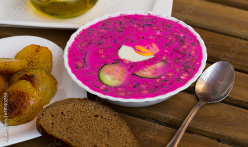 Traditional Belarusian cold vegetable soup Holodnik served with baked potatoes and brown bread on wooden background.. photo