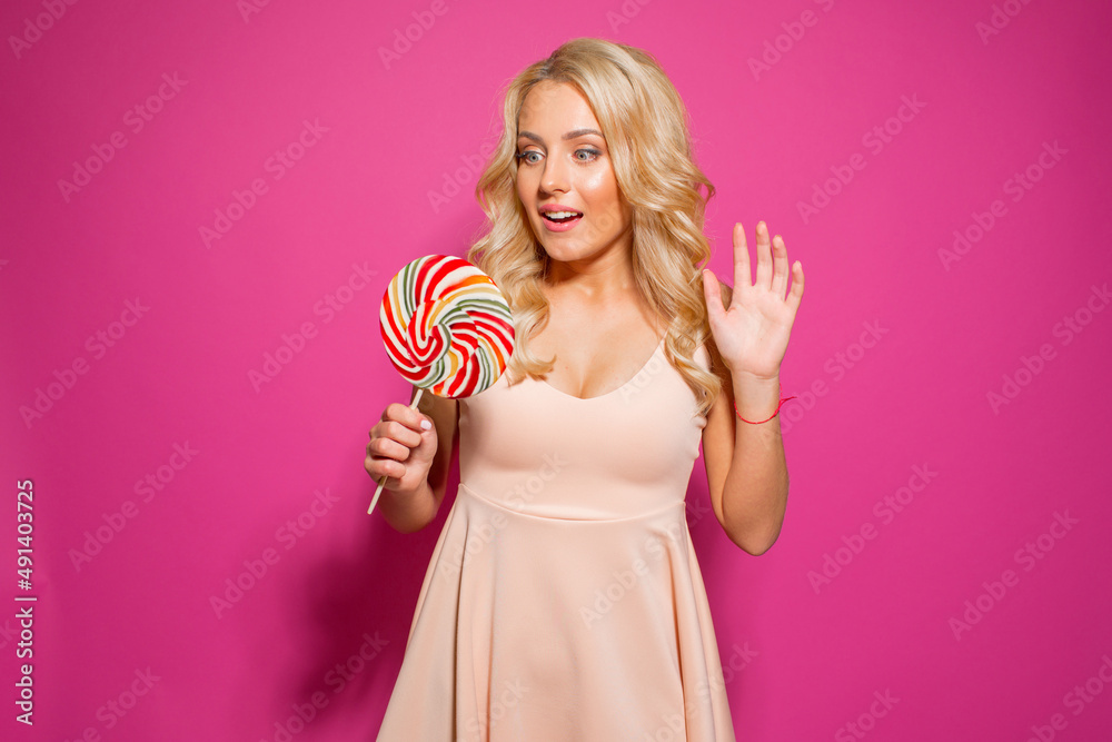 Beautiful happy girl with a big candy on a bright background