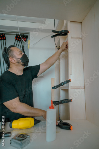 Man using clamps to hold workpiece gluing. DIY project at home.