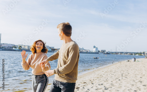 two young people in love running on the beach. They smile at each other. Beautiful couple holding hands. Beach. Feeling. Dress in a sweater