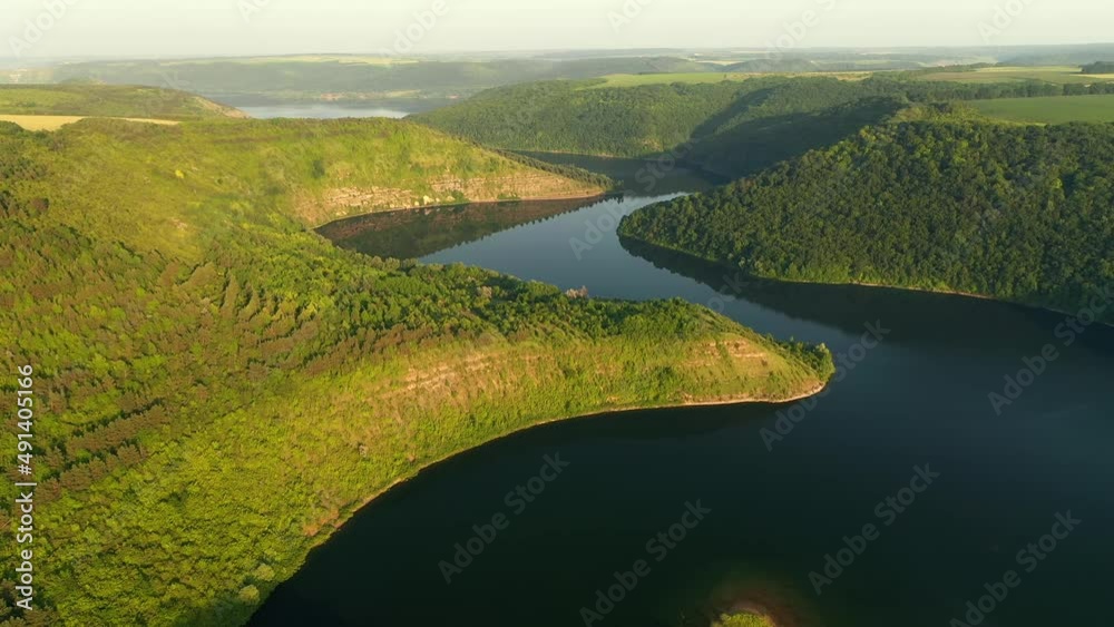 Panoramic view of the meandering river flowing through the green hills from a bird's eye view. Filmed in UHD 4k video. Panoramic view of the meandering river flowing through the green hills from a bird's eye view. Filmed in UHD 4k video.