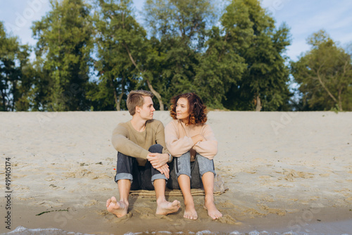A loving couple has fun - they laugh, hug each other and enjoy a warm summer evening. Romantic couple sitting by the sea. The guy and the girl look at each other