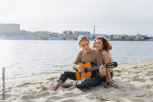 Happy couple in love. Stunning sensual portrait of a young couple. Young man playing guitar for his beloved girl.