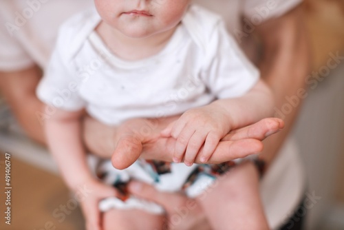 hands of father and mother hold small palm of their child, faceless close-up