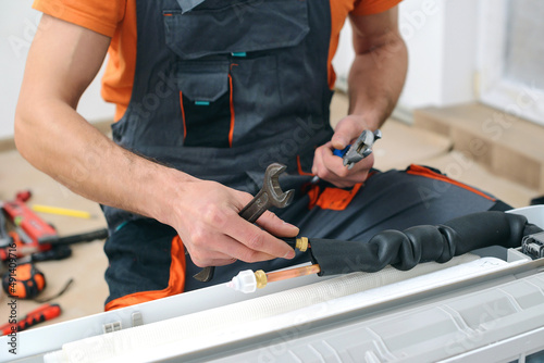 Worker installs indoor unit of the air conditioner. Man preparing to install new air conditioner.