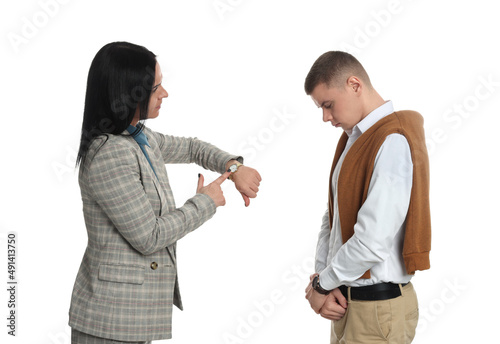 Businesswoman pointing on wrist watch while scolding employee for being late against white background