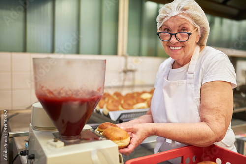 Frau als Bäcker beim Füllen von Berliner Pfannkuchen