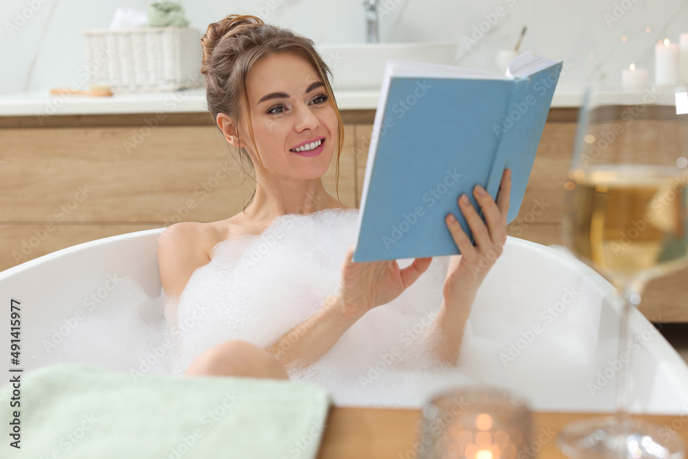 Beautiful woman reading book while enjoying bubble bath at home Beautiful woman reading book while enjoying bubble bath at home
