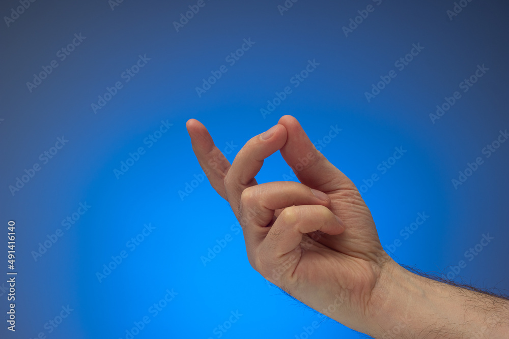 Finger snap gesture by Caucasian male hand. Close up studio shot, isolated on blue background Finger snap gesture by Caucasian male hand. Close up studio shot, isolated on blue background