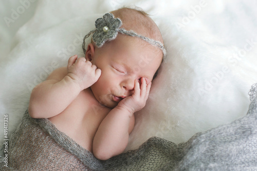 A newborn in a gray cloth sleeps on a white blanket. Happy childhood. Child
