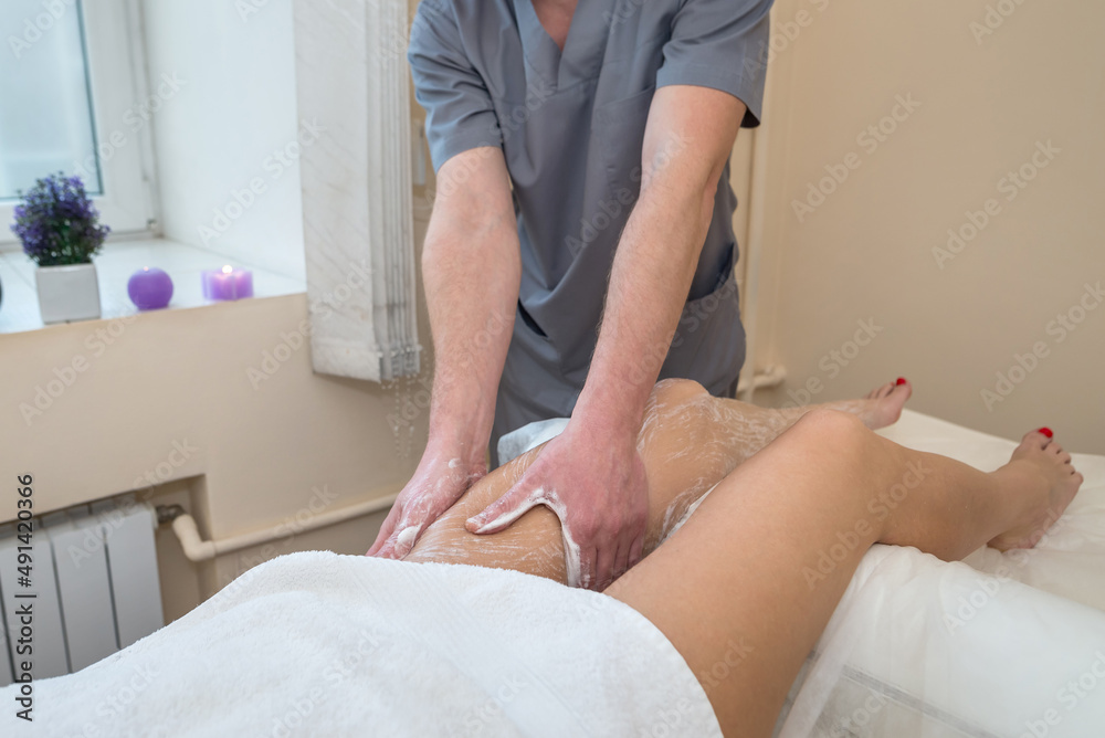 Fototapeta premium foot scrub in spa salon.Male massage therapist applies cleansing scrub on young girl's feet.