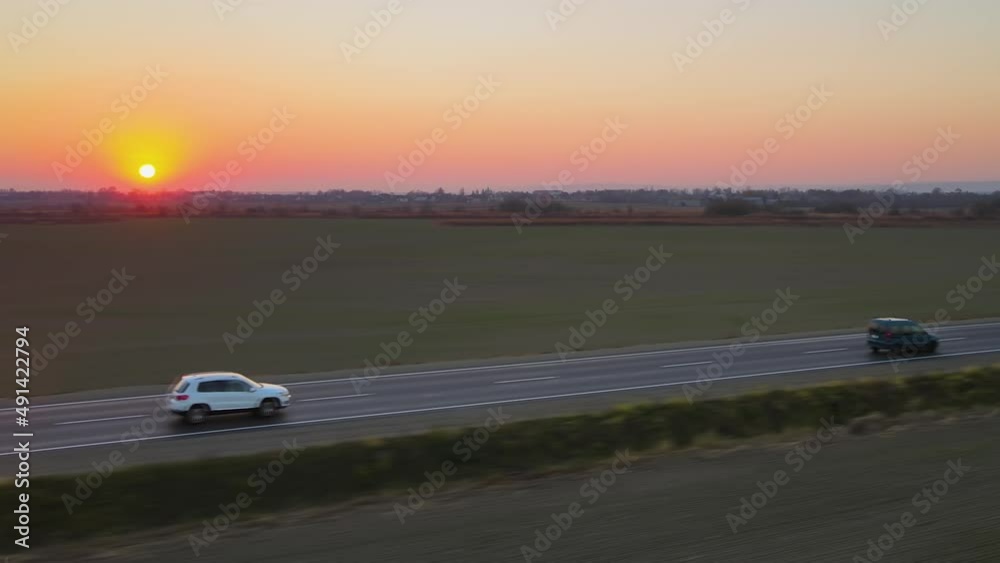 Aerial view of intercity road with fast driving cars at sunset. Top view from drone of highway traffic in evening Aerial view of intercity road with fast driving cars at sunset. Top view from drone of highway traffic in evening